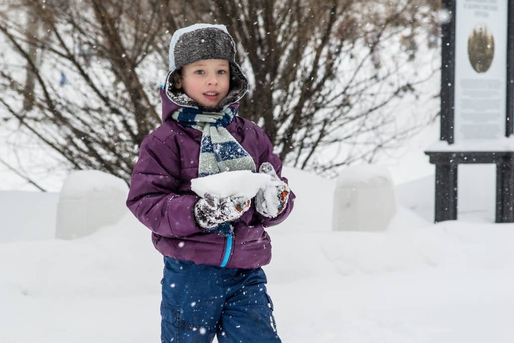 Na zdjęciu chłopiec podczas zabawy śniegiem